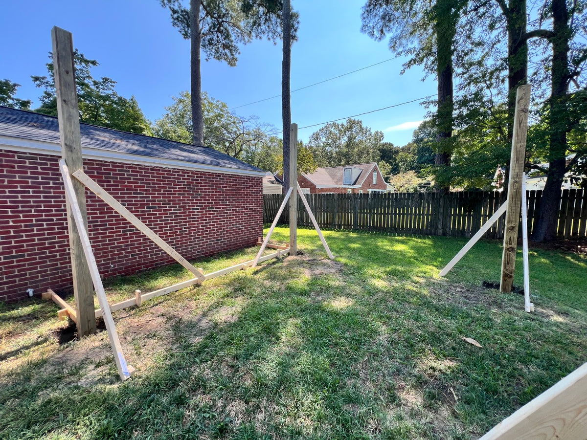 Wooden posts and bracing installed in a residential backyard, part of an outdoor carpentry or structural project