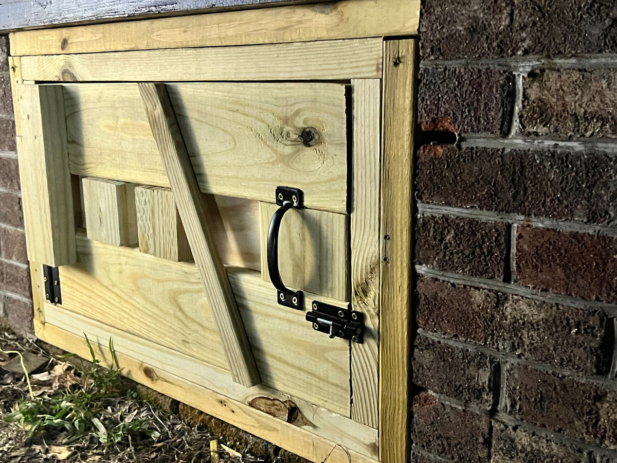 Completed custom crawl-space door, angled view showing hardware