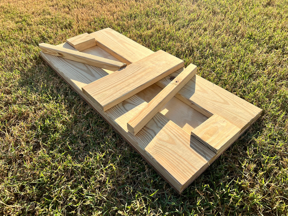 Custom crawl space door on grass — three-quarter angle showing diagonal brace mid-assembly